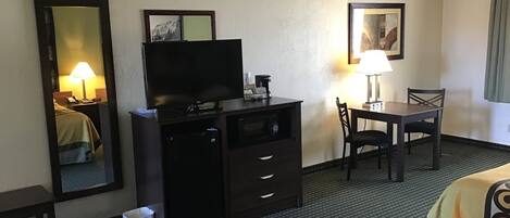 Habitación de hotel con cama, televisor en una cómoda, escritorio con silla y lámpara.