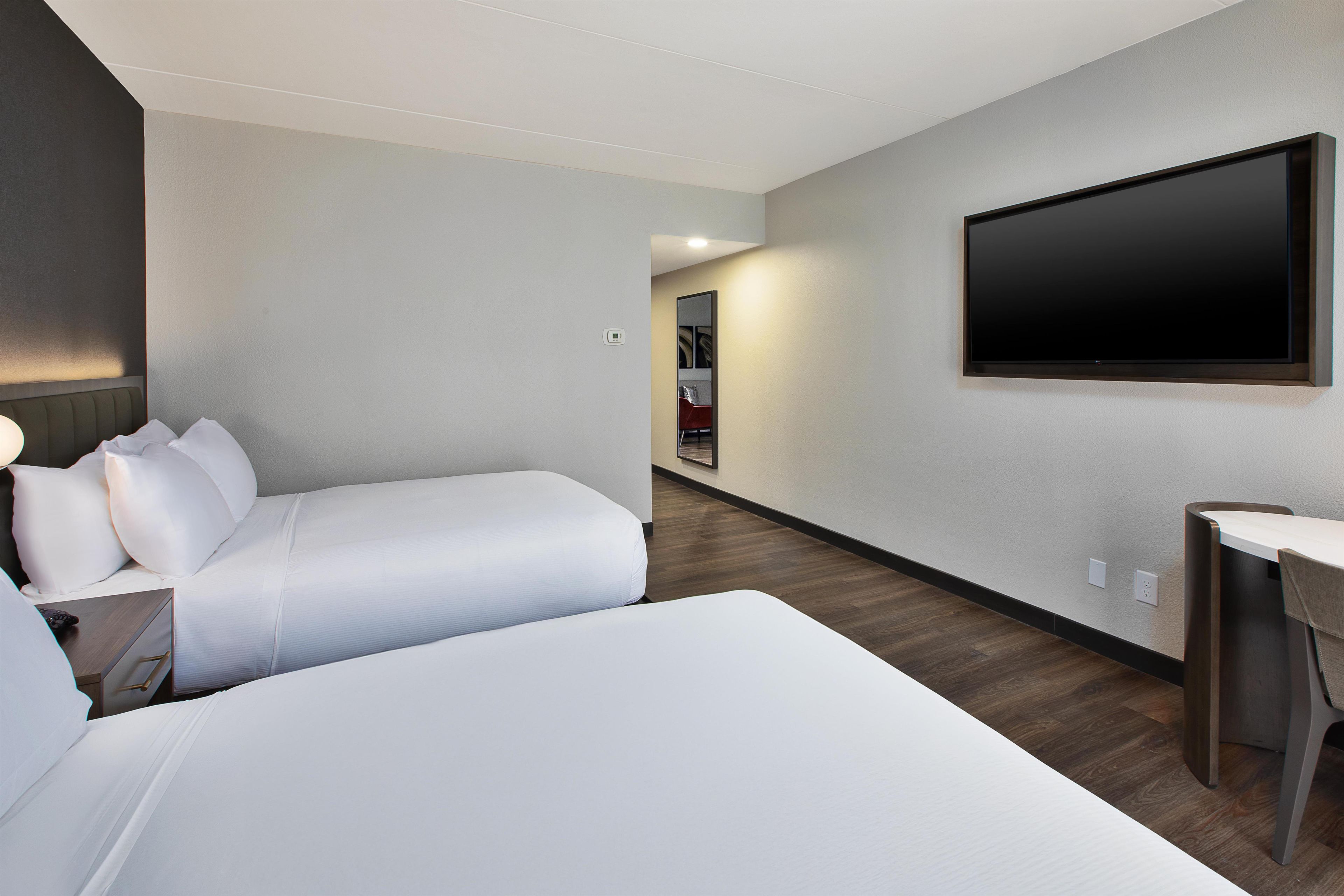 Habitació d'hotel amb dos llits, un televisor de pantalla plana fixat a la paret i una taula petita.