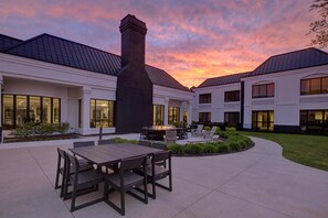 A modern building with a patio area featuring a table and chairs, a fire pit, and a chimney. - DoubleTree by Hilton Detroit Novi (Novi)