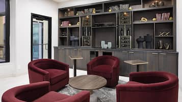 A modern interior with a seating area, dark wood shelving with books and decorative items, and a glass door leading outside.