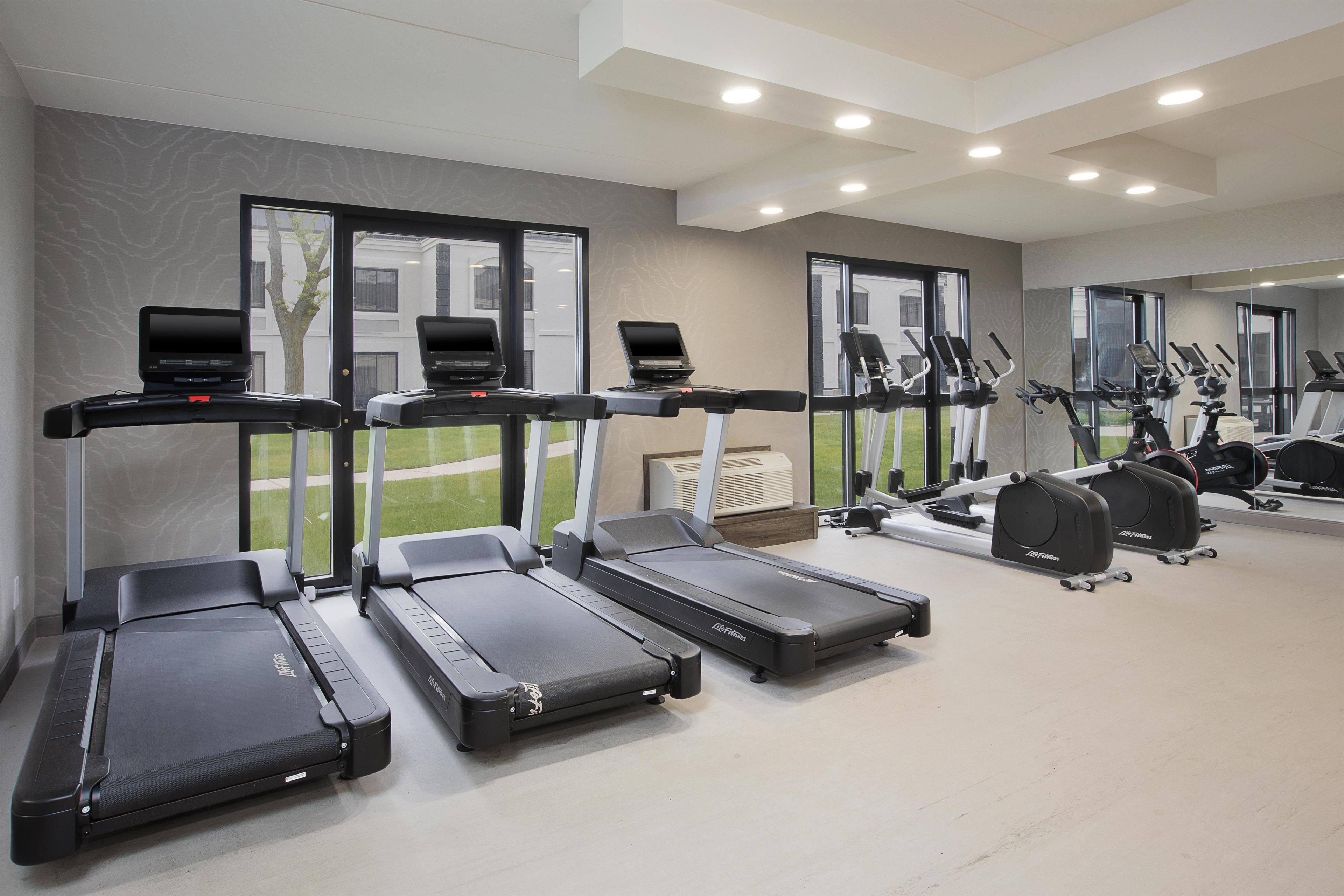 A gym with multiple treadmills, exercise bikes, and a mirrored wall.
