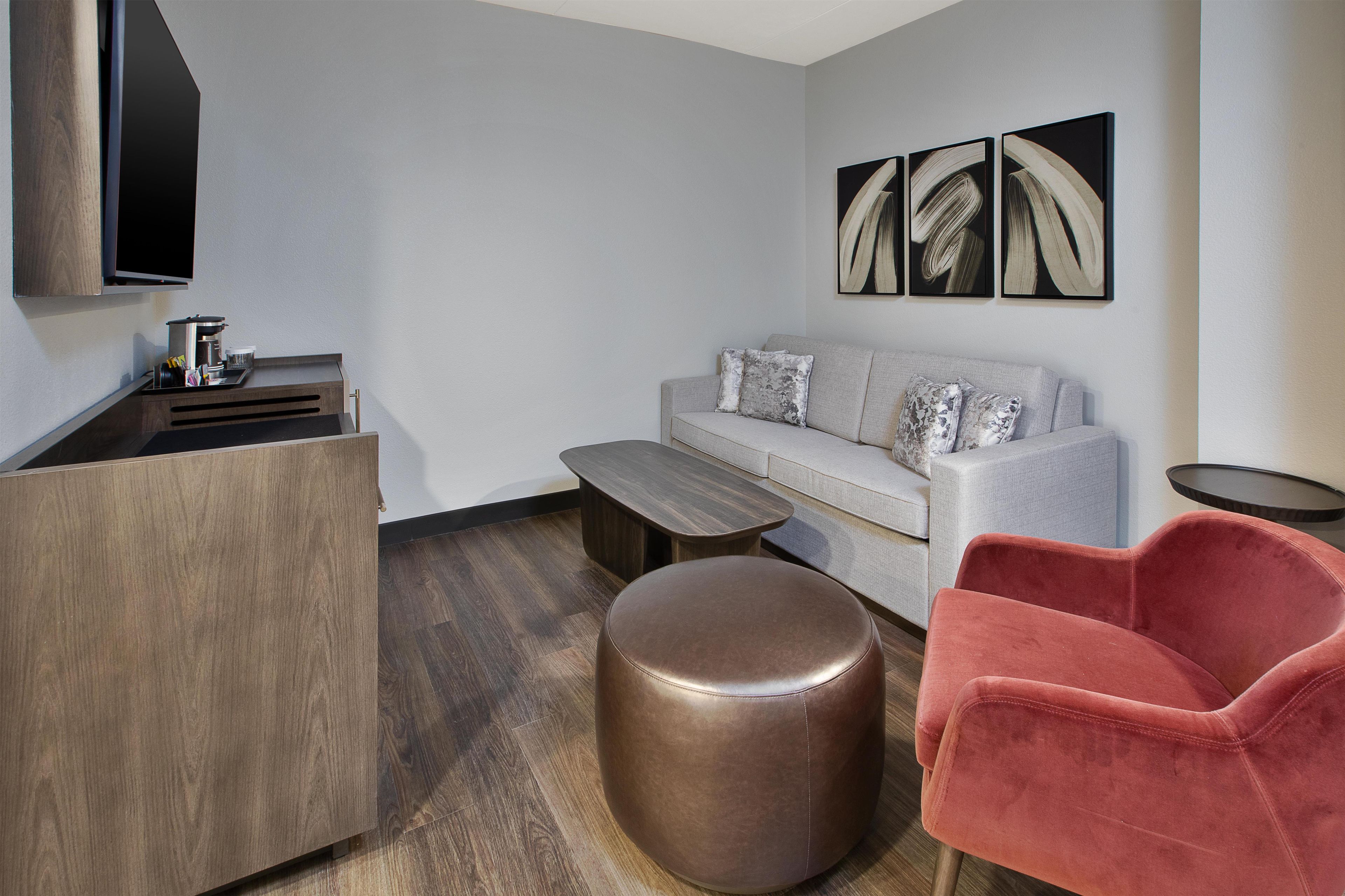 A modern living room with a sofa, ottoman, and a red chair.