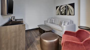 A modern living room with a sofa, ottoman, and a red chair.