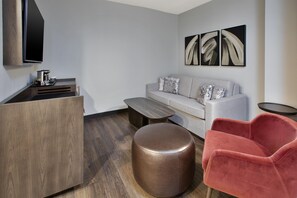 Uma sala de estar moderna com sofá, banqueta e uma poltrona vermelha.