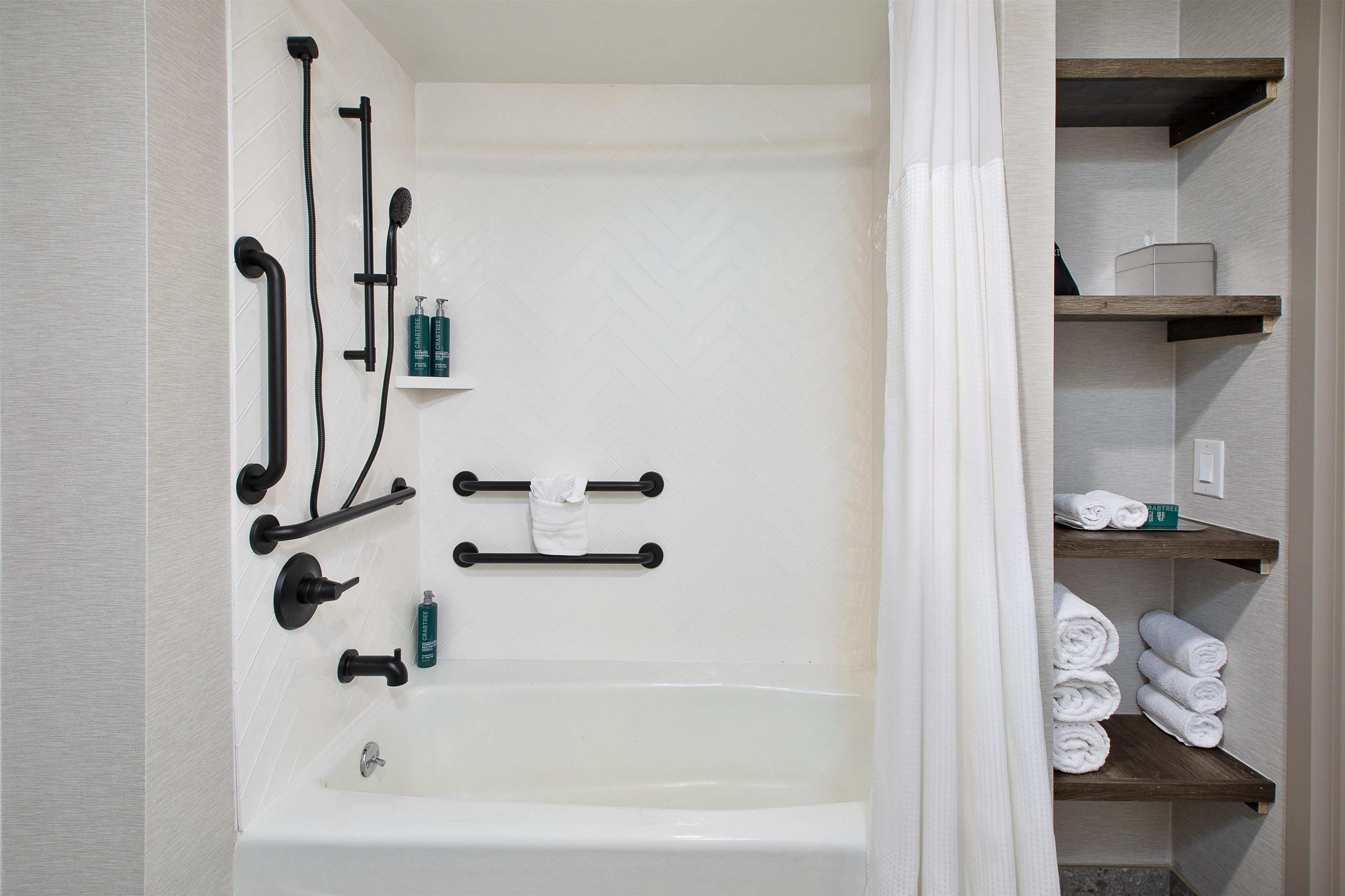 Ein Badezimmer mit Badewanne, Handtuchhalter und Ablagen für Toilettenartikel.