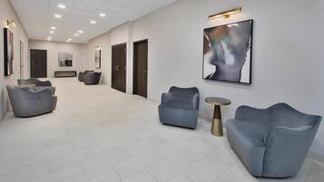 A spacious lobby with modern seating, a large abstract painting, and a clean, tiled floor.