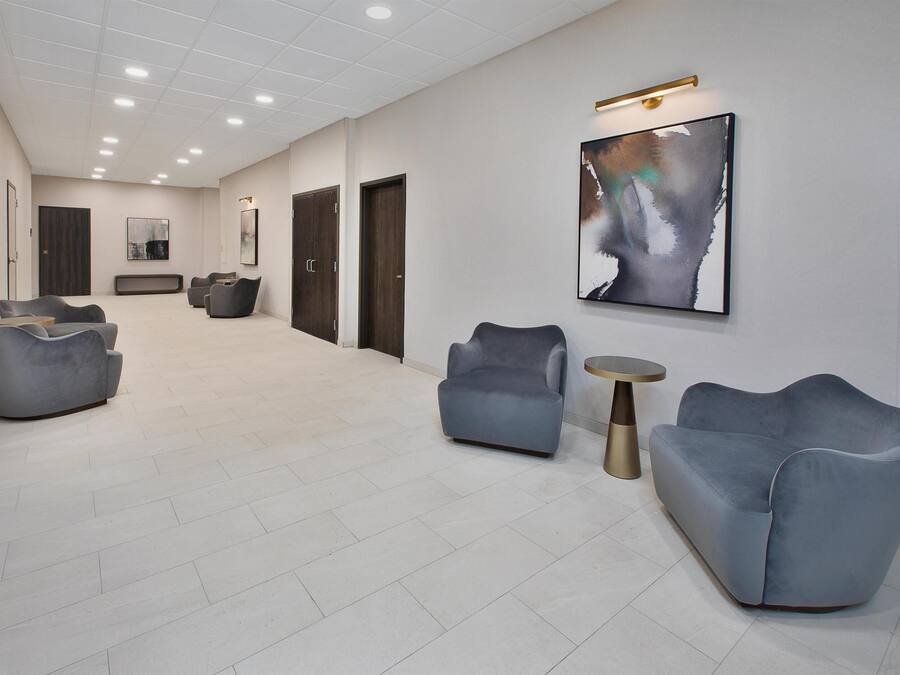 A spacious lobby with modern seating, a large abstract painting, and a clean, tiled floor.