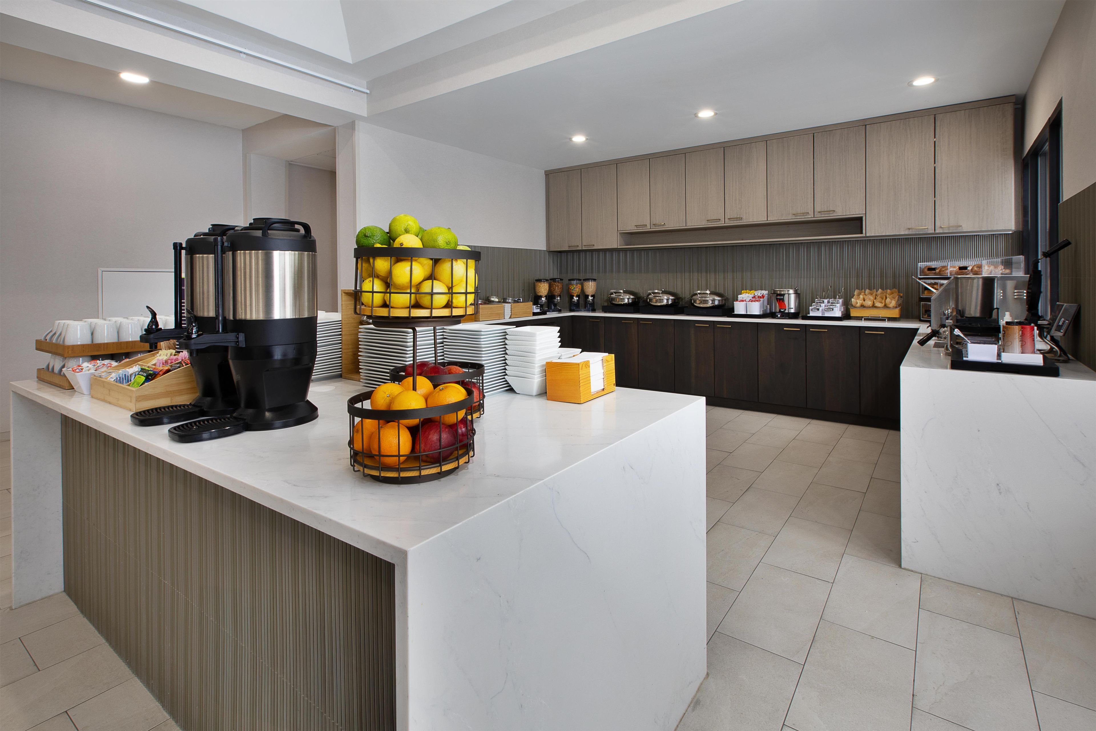 Une cuisine moderne dotée d’un îlot central, équipée d’une machine à café, de corbeilles à fruits et d’un buffet.