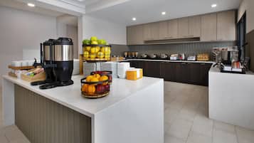 Une cuisine moderne dotée d’un îlot central, équipée d’une machine à café, de corbeilles à fruits et d’un buffet.