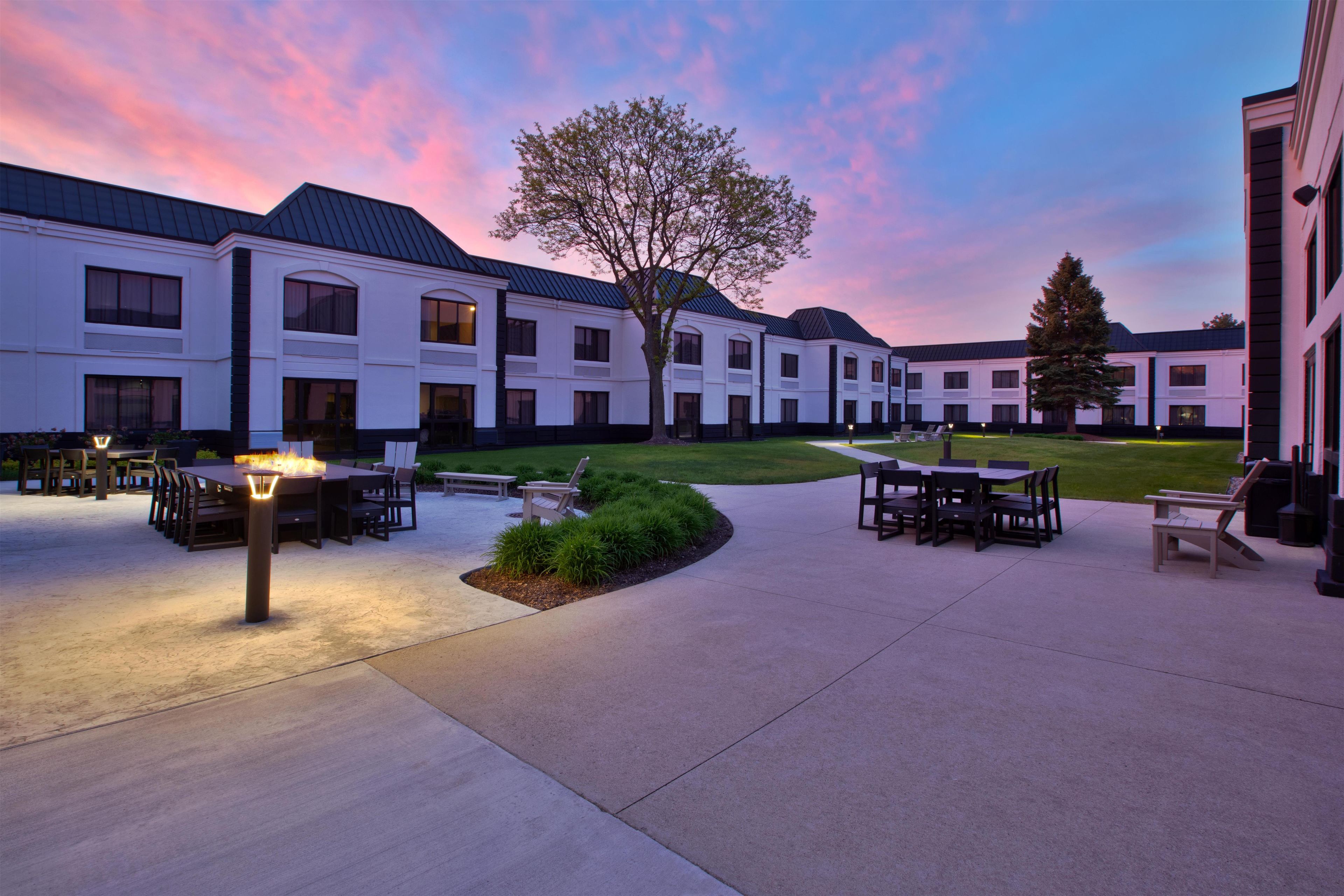A courtyard with outdoor seating, a fire feature, and a building with multiple windows.