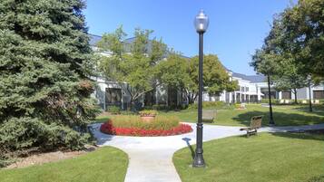A pathway leading to a building with a well-maintained lawn, a bench, and a street lamp.