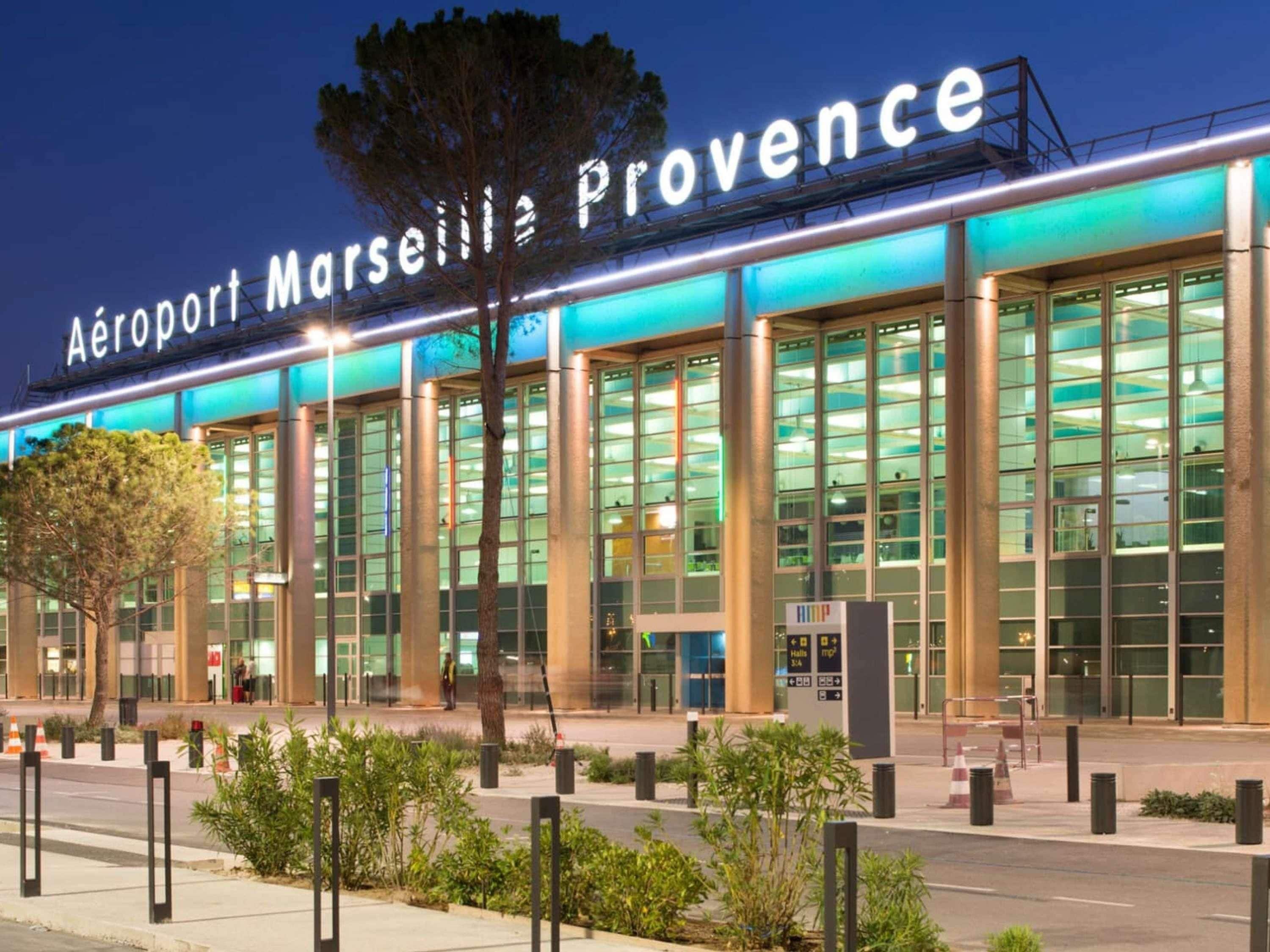 Um edifício moderno com grandes janelas e uma placa com a inscrição 'Aéroport Marseille Provence'.