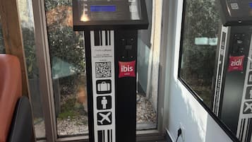 Balanza de equipaje con pantalla digital, un código QR e iconos de maletas, una persona y un avión, que indica que sirve para consultar información de equipaje.