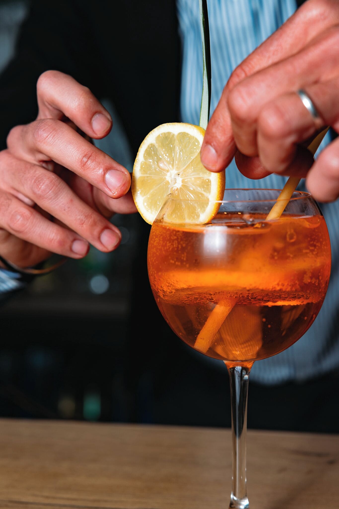 Une personne tenant un verre à cocktail, décoré d’une tranche de citron.