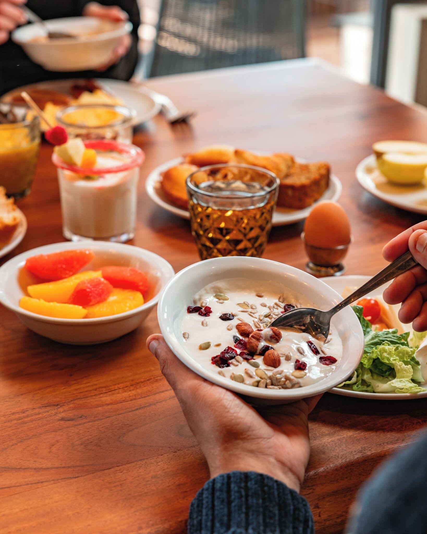 Un tavolo da pranzo con diversi piatti, tra cui una ciotola di cereali con frutta e noci, un bicchiere di succo e un piatto di pane.