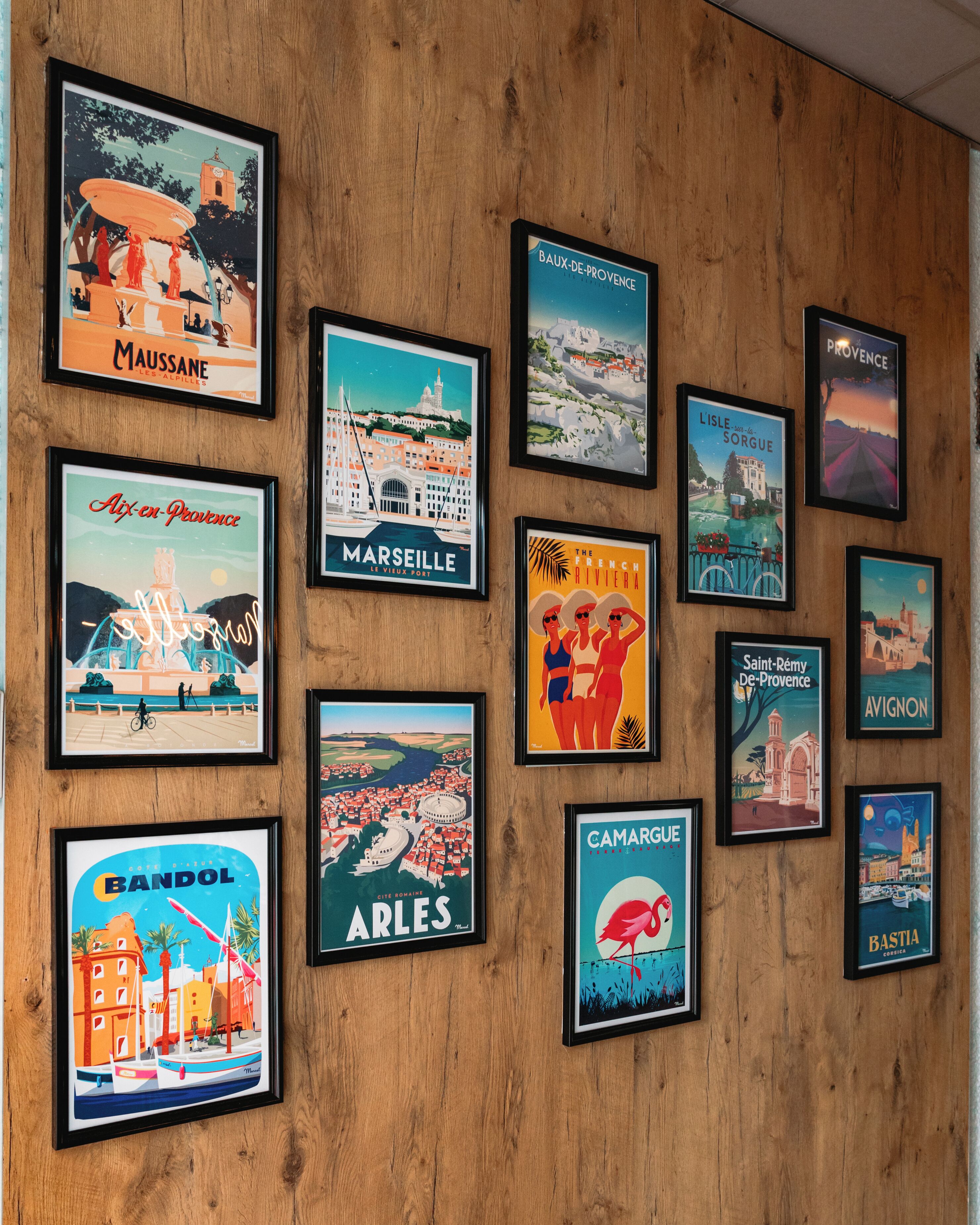 A collection of framed travel posters on a wooden wall.