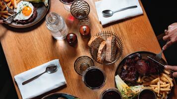 A wooden dining table with various dishes, including steak, fries, and a salad.