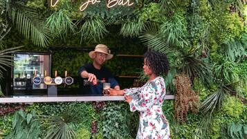 Eine Bar mit einem Neon-Schild, das "Ve Jo Bar" zeigt, und verschiedenen Zapfhähnen für Bier.