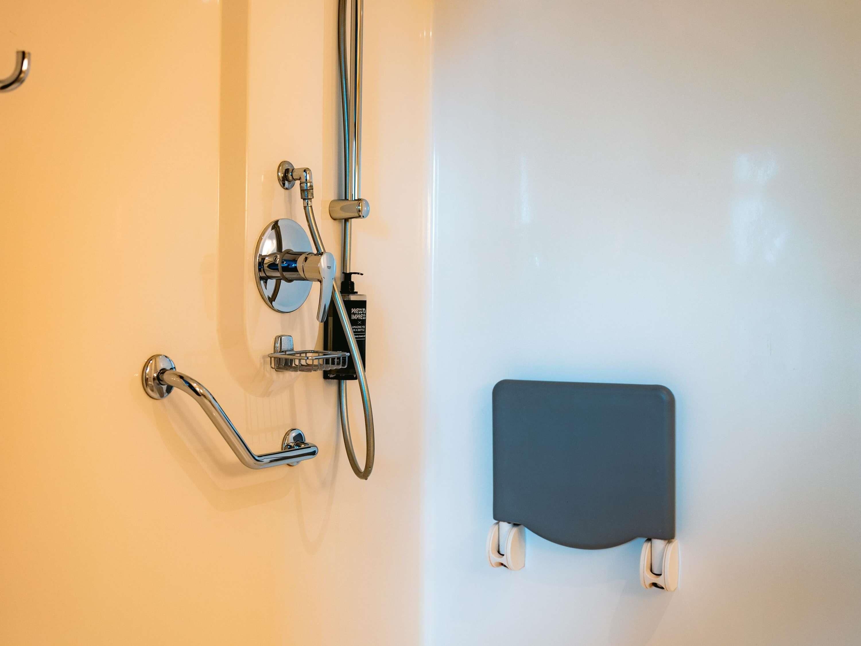 A shower with chrome fixtures, a handheld showerhead, and a handheld shower control.