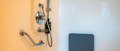 A shower with chrome fixtures, a handheld showerhead, and a handheld shower control.