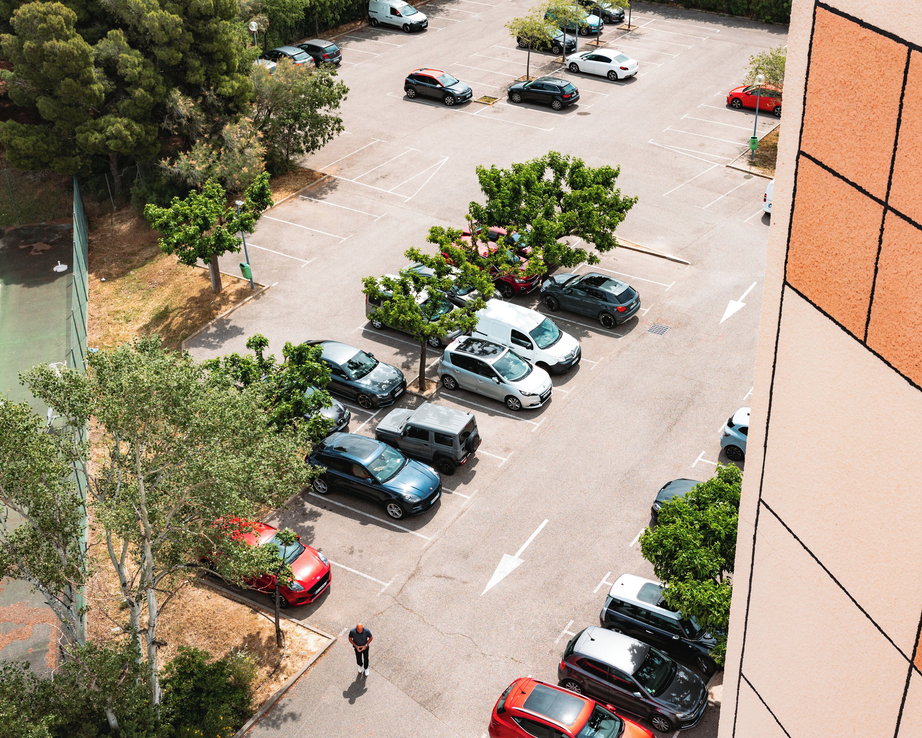 Un pàrquing amb diversos cotxes i alguns arbres.