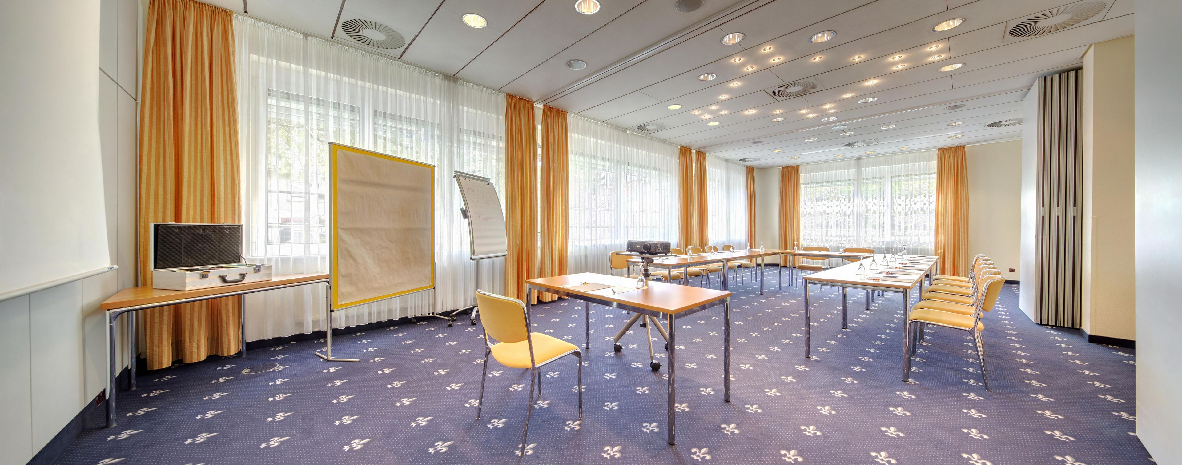 A conference room with a large table, chairs, a projector, and a whiteboard.