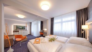 A hotel room with two beds, a desk, a chair, and a large window with curtains. - Best Western Plus Hotel Steinsgarten (Giessen)