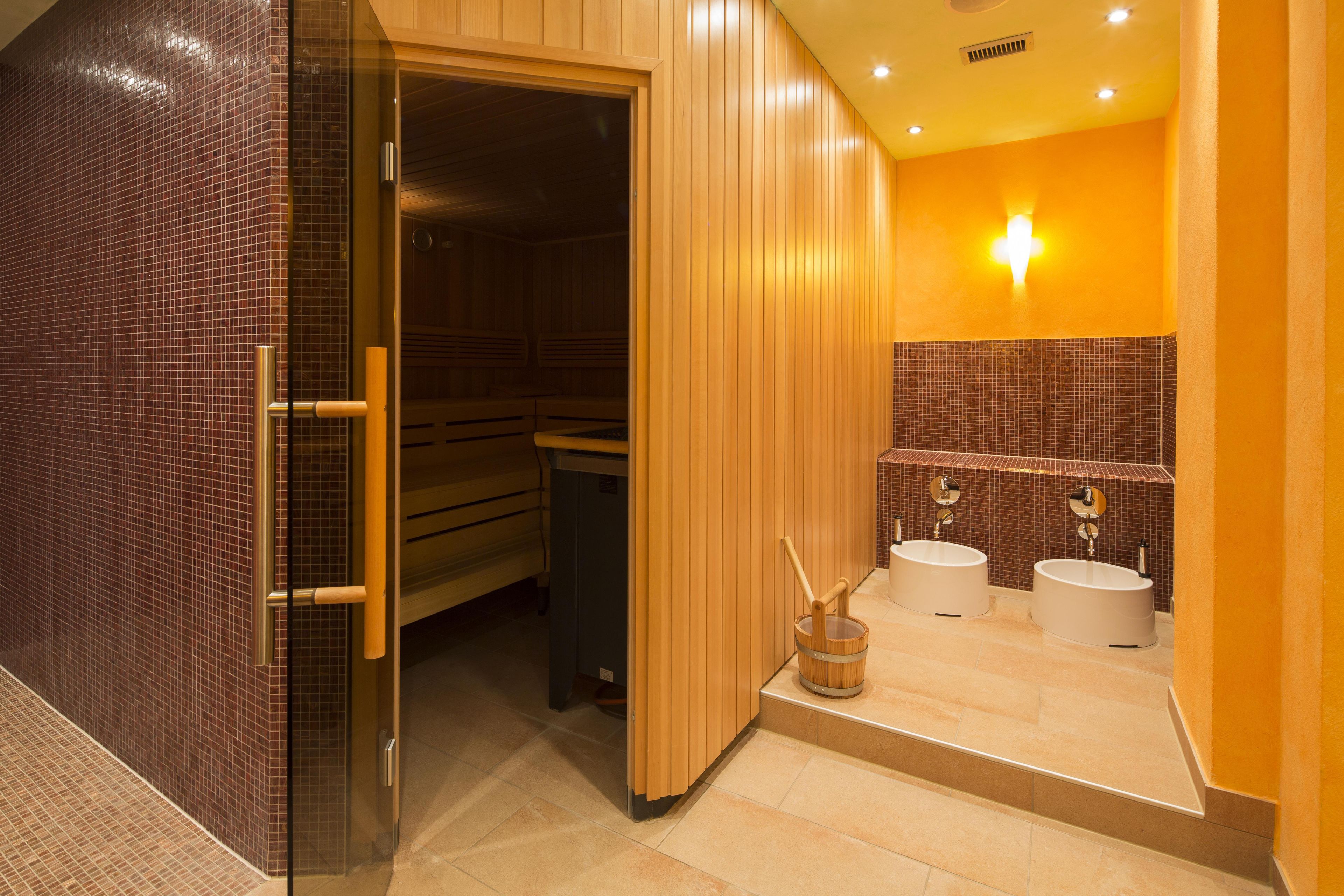 Una sala de sauna con bancos de madera y pared de azulejos.