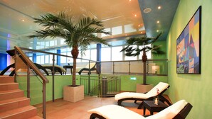 A modern indoor space with a staircase, lounge chairs, and potted palm trees. - Best Western Plus Hotel Steinsgarten (Giessen)