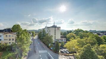 Straßenansicht mit einem Hotel namens 'Hotel Steinbock' im Zentrum, umgeben von Bäumen und anderen Gebäuden.