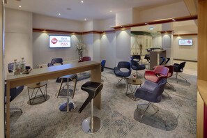 A hotel lobby with a reception desk, several chairs, a small table with a vase, and a sign on the wall. - Best Western Plus Hotel Steinsgarten (Giessen)