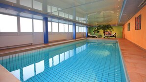 An indoor swimming pool with clear blue tiles, a glass ceiling, and a view of the sky. - Best Western Plus Hotel Steinsgarten (Giessen)