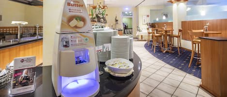 A buffet area with a self-service butter station, stacked plates, and a seating area with tables and chairs.