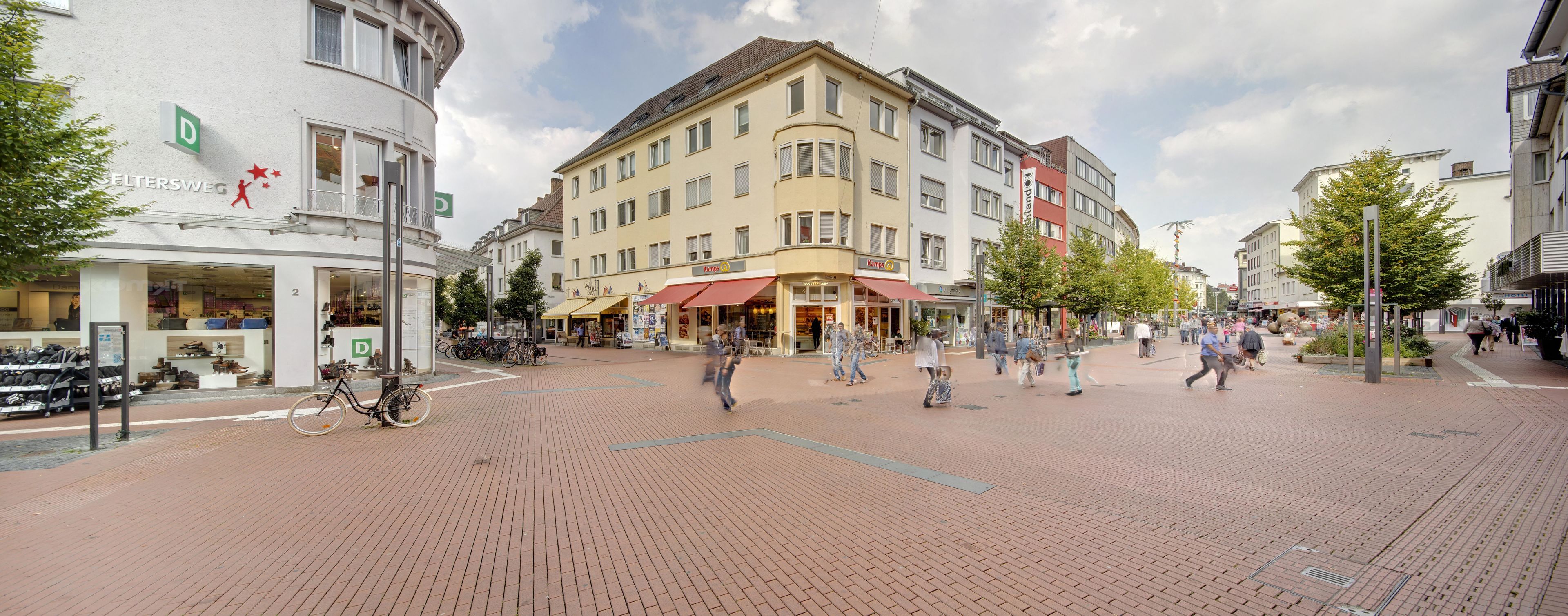 A pedestrian area with shops and a building with a curved facade.