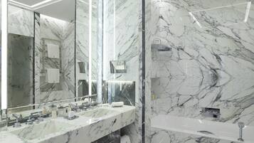 Een moderne badkamer met marmeren wanden, een grote spiegel en een wastafel met twee kommen.