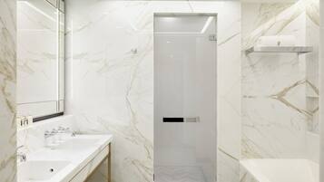 A modern bathroom with a marble backsplash, a large mirror, a vanity with a sink, and a shower area.
