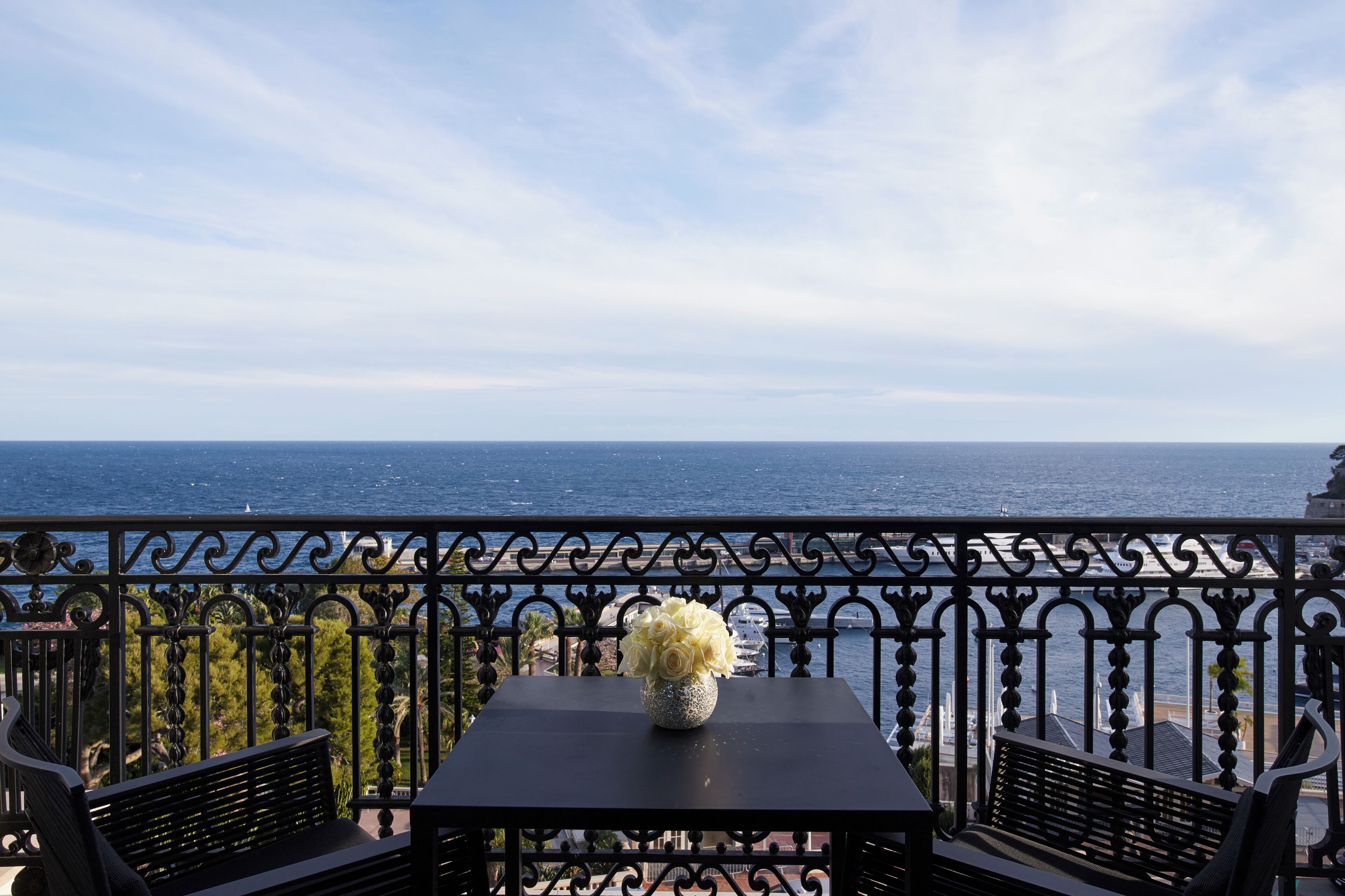 A balcony with a table and chairs, overlooking a body of water.
