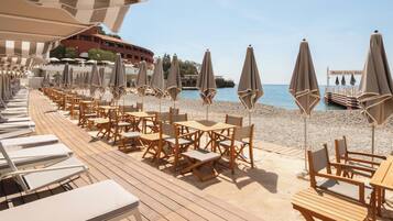 Relax on the beachfront deck with comfortable seating under shaded umbrellas.