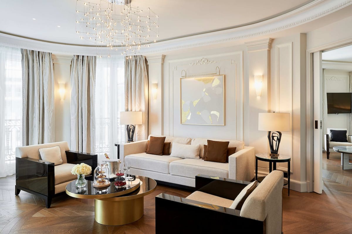 A modern living room with a sofa, armchairs, a coffee table, and a chandelier.