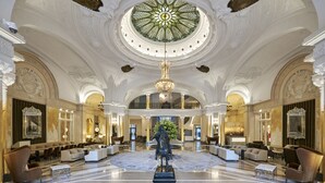 Een statig atrium met een centraal standbeeld, een versierd plafond en een groot rond raam.