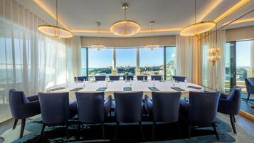 A conference room with a panoramic city view, large round tables, and modern lighting fixtures.