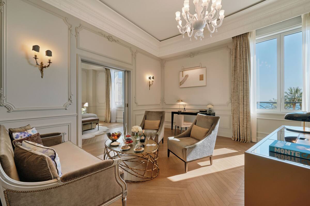 A spacious living room with a sofa, armchairs, a coffee table, and a chandelier.