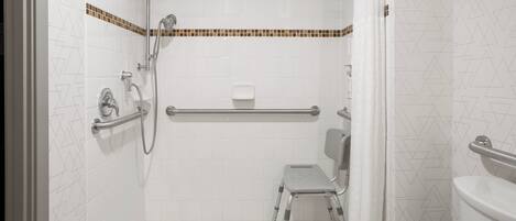 A bathroom with a shower, toilet, and grab bar.