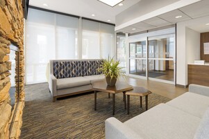 A modern lobby with a sofa, a coffee table, and a potted plant.