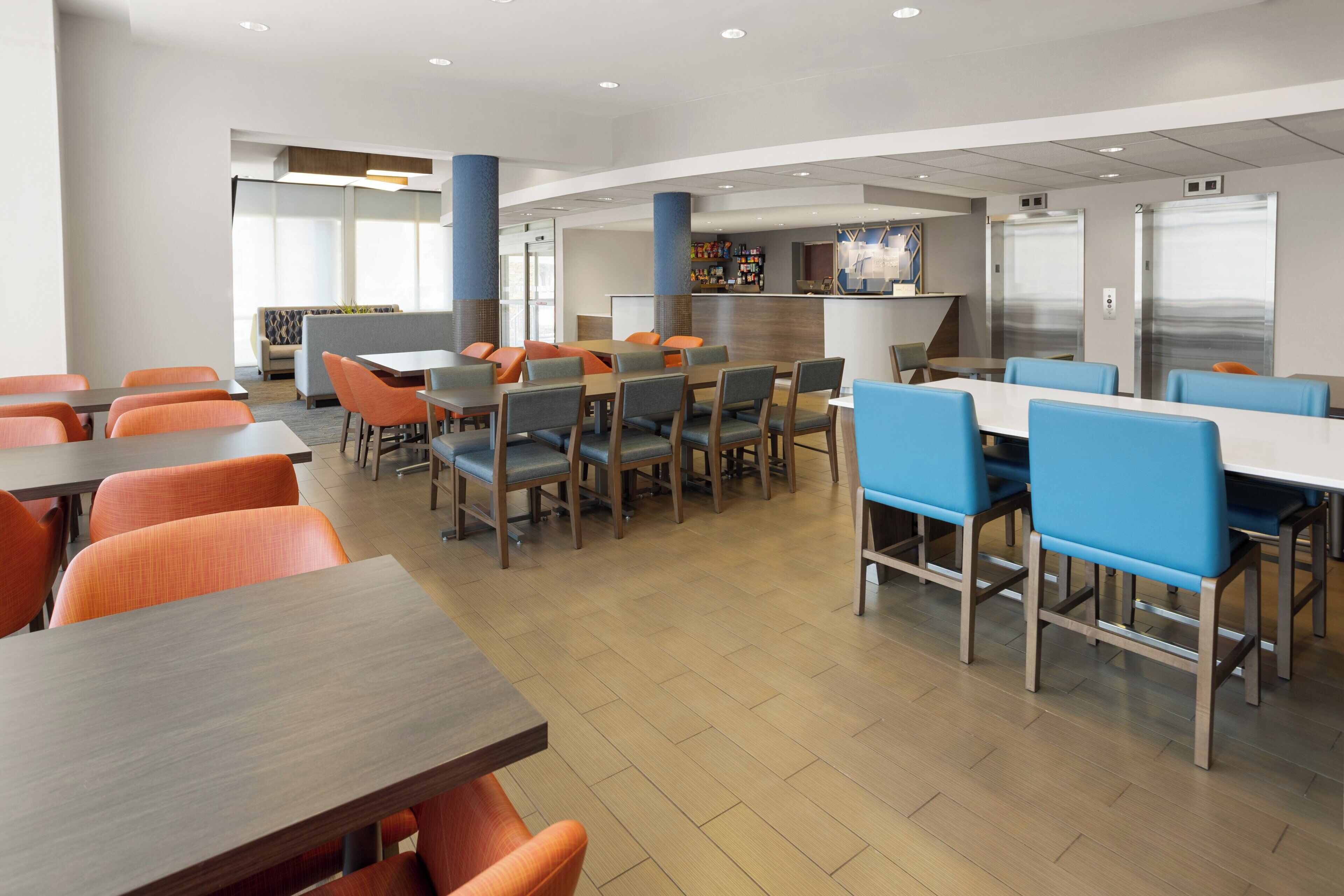 A modern dining area with multiple tables and chairs, a bar area, and a seating section with a view.