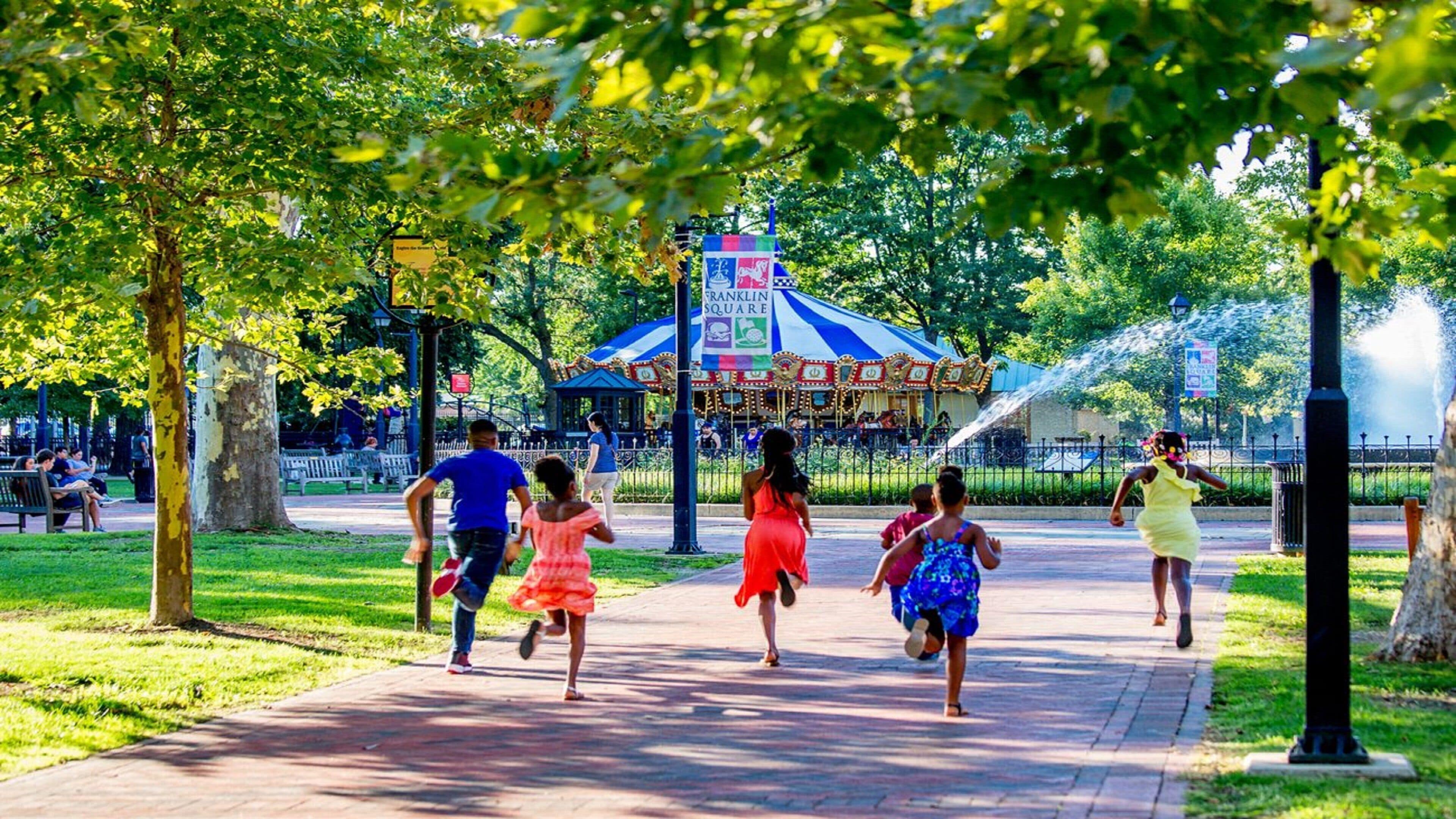 A park with a carousel, trees, and a paved walkway.