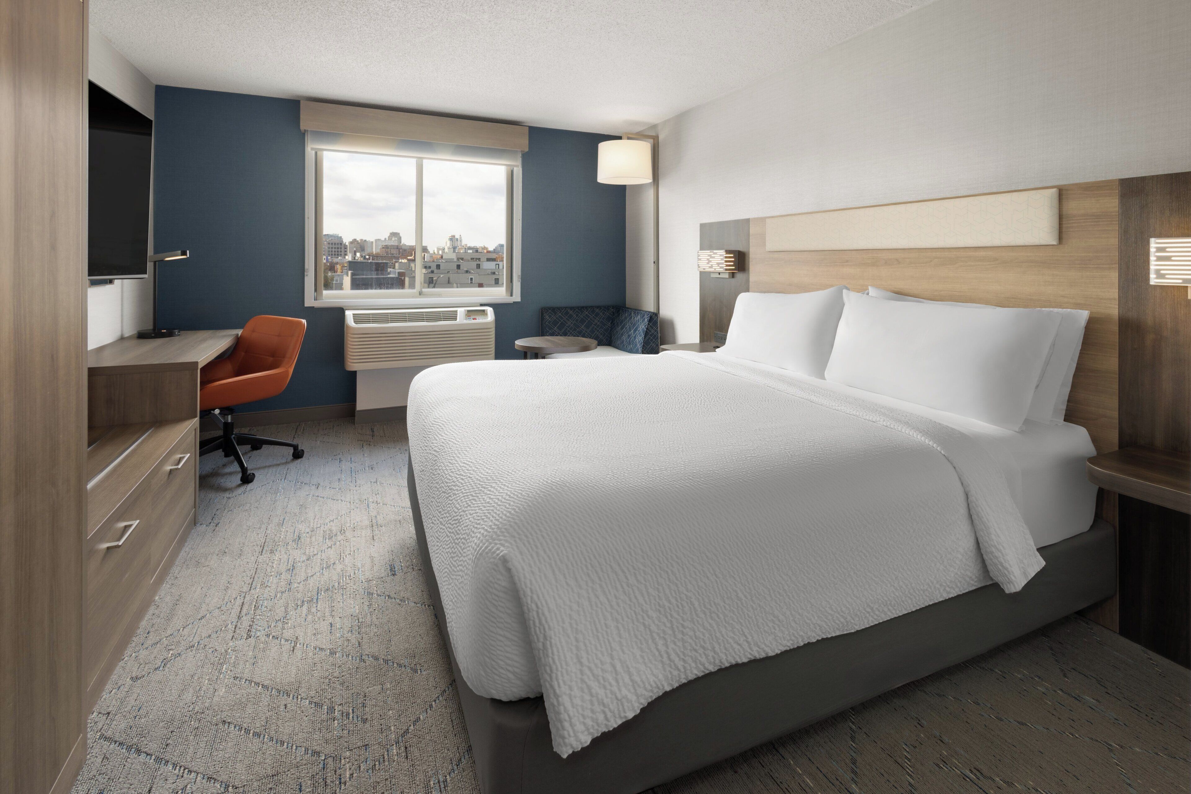 A modern hotel room with a large bed, a desk, and a chair.