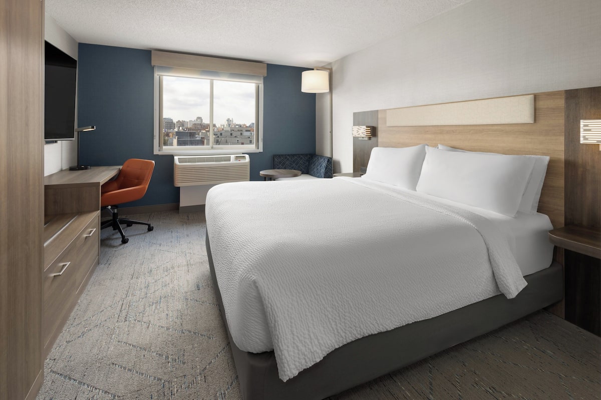 A modern hotel room with a large bed, a desk, and a chair.