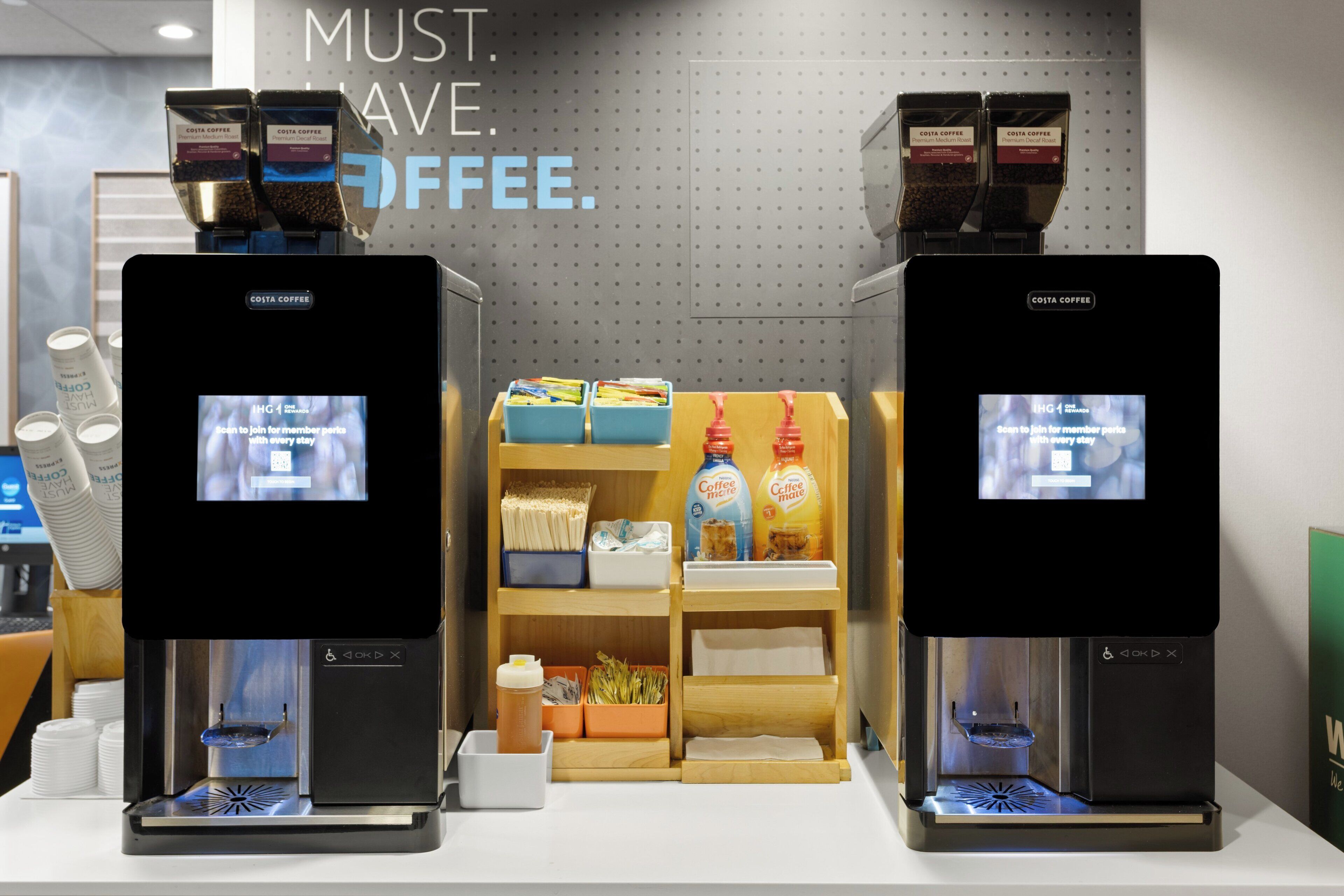 Two coffee machines with digital displays, a shelf with coffee products, and a sign that reads "MUST SAVE COFFEE."