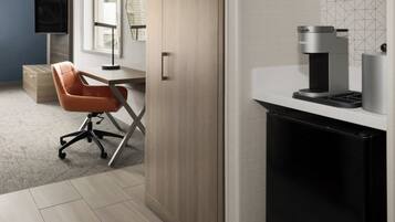 A modern office space with a desk, chair, coffee machine, and a television.